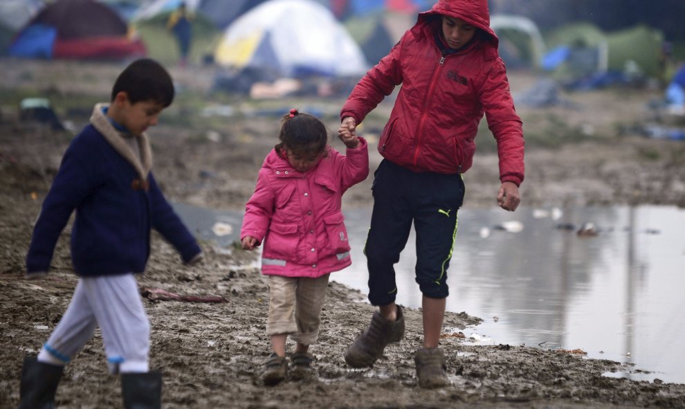 Niños caminan por el barro en un campo de refugiados cerca de Idomeni (Grecia) en la frontera con Macedonia.- EFE