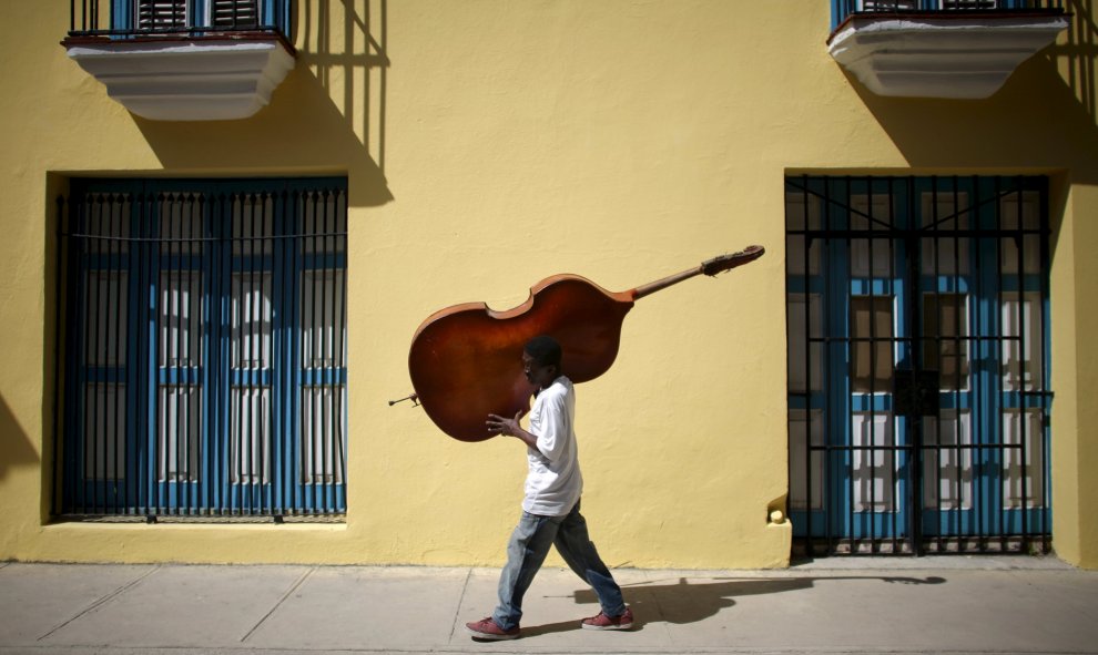 El músico Frilal Ortiz lleva un cello en el centro de La Habana. REUTERS/Alexandre Meneghini