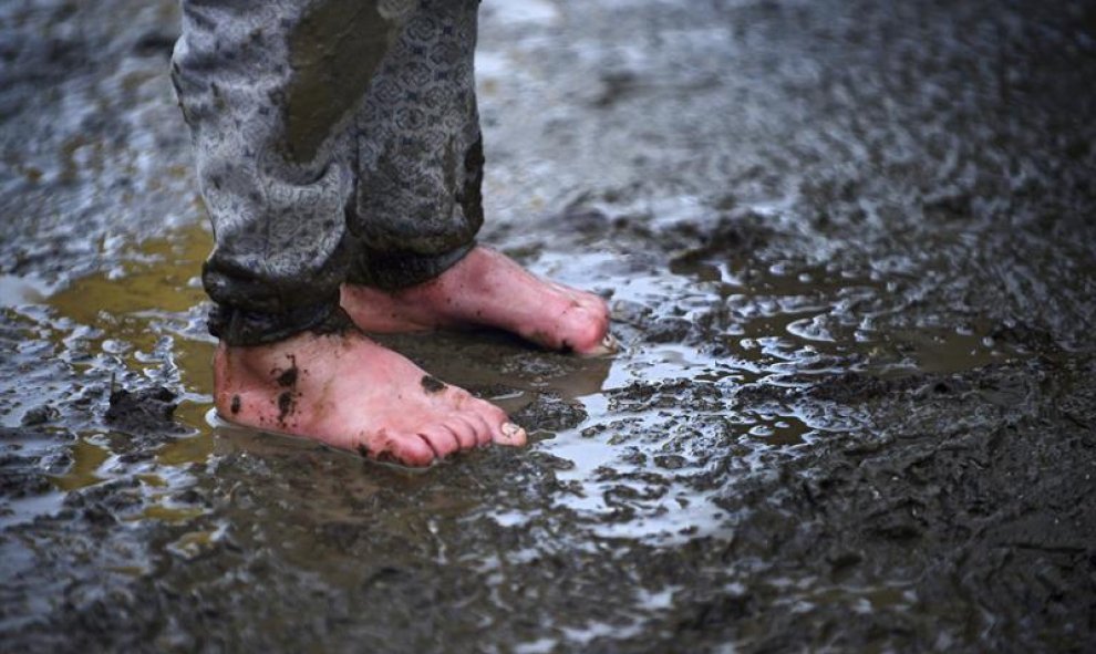 Un niño permanece en pie en el barro en un campo de refugiados cerca de Idomeni, Grecia. EFE/Nake Batev