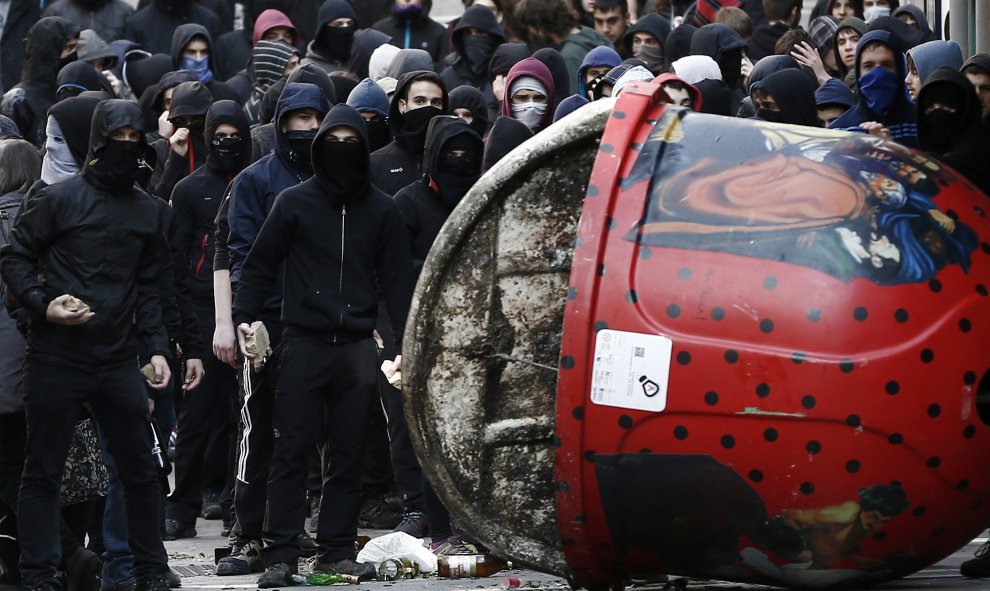 Un grupo de jóvenes curzan un contenedor en la calle Mercaderes donde se han producido enfrentamientos con la Policía Nacional al termino de una manifestación de estudiantes que se ha celebrado en Pamplona en el marco de una jornada de protestas convocada