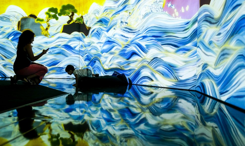 Una visitante fotografía a su hijo mientras interactua con la obra de luces llamada 'Mar de 100 años' que forma parte de una instalación mostrada en la feria 'Future World' en el Museo de las Artes y las Ciencias de Singapur. EFE/Wallace Woon