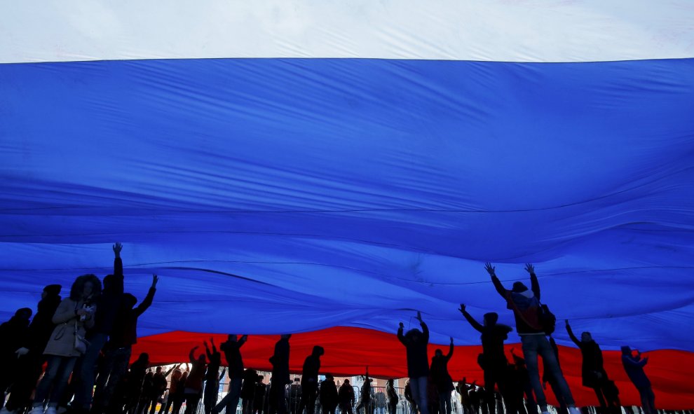 Personas sostienen una bandera nacional de Rusia durante el concierto festivo que marca el segundo aniversario de la anexión a Rusia de la región de Crimea, en el centro de Moscú. REUTERS/Maxim Shemetov