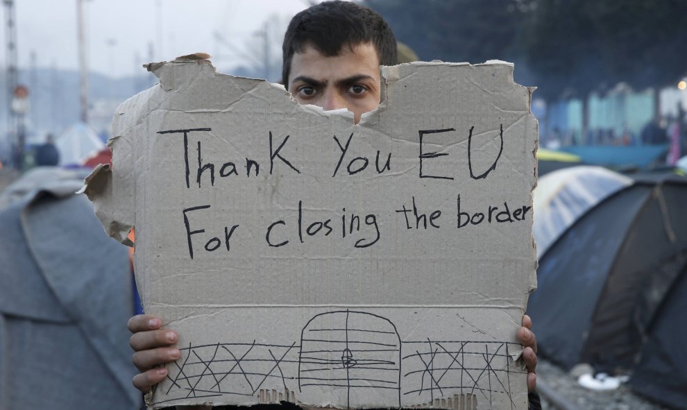 Un refugiado sostiene un mensaje en un campamento improvisado en la frontera entre Grecia y Macedonia, cerca de la localidad de Idomeni.  REUTERS/Alkis Konstantinidis TPX IMAGES OF THE DAY