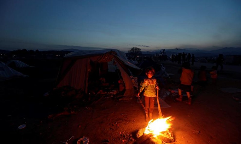 Varios refugiados encienden un fuego en un campo de la frontera entre Grecia y Macedonia en Idomeni, Grecia. EFE