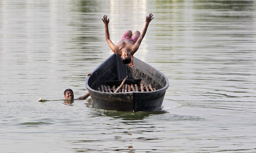 Un niño salta de un barco en un lago en Agartala, India. REUTERS/Jayanta Dey