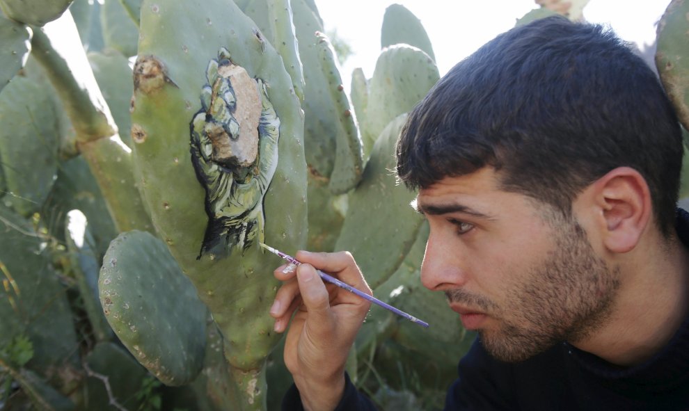 El artista palestino Ahmad Yasin pinta sobre un cactus en su jardín de la casa en la aldea cisjordana de Naplusa 31 de marzo de 2016. REUTERS / Omar Abed Qusini