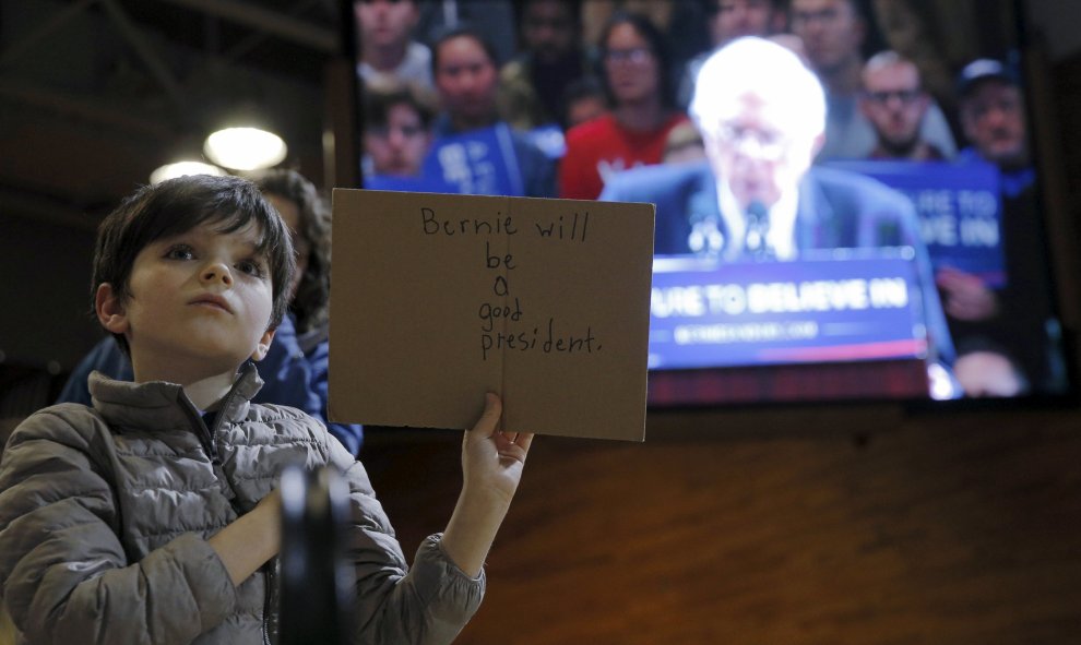 Un niño sostiene un cartel escrito que dice "Bernie será un buen presidente", en referencia al candidato demócrata a la presidencia estadounidense Bernie Sanders, mientras este habla en un acto de campaña en Poughkeepsie, Nueva York. REUTERS/Brian Snyder