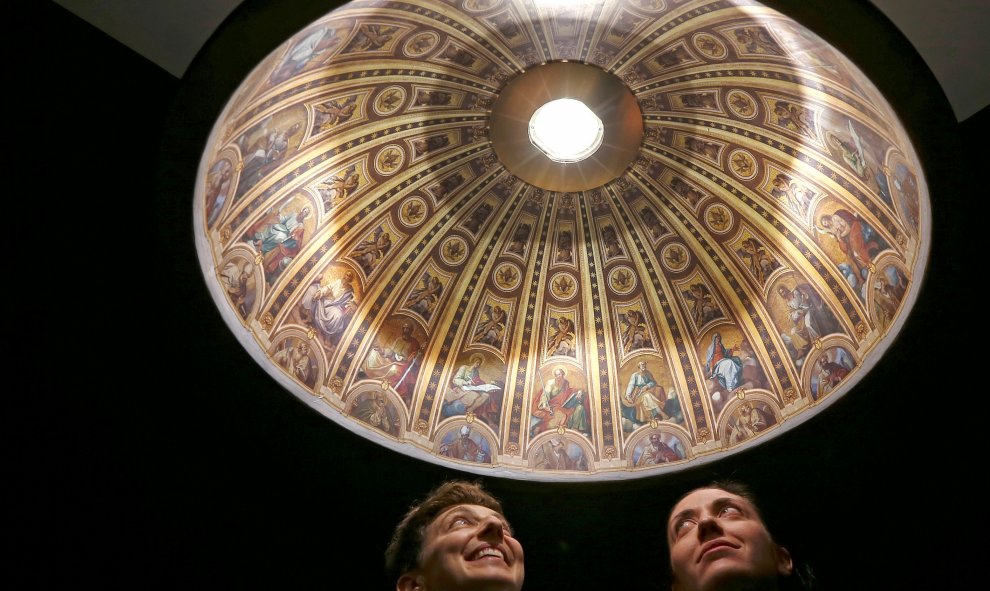 Las diseñadoras italianas Eleonora Barbareschi (izquierda) y Alessandra Mantovani posan debajo de una lámpara decorada con una reproducción hiperrealista de la Basílica de San Pedro para la Semana del Diseño de Milán. REUTERS/Stefano Rellandini