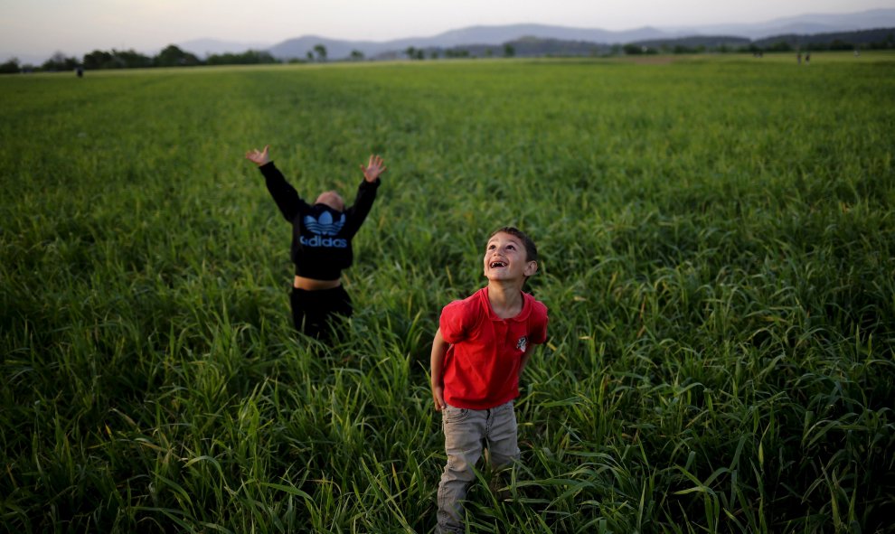 Unos niños miran al cielo mientras juegan con una cometa junto a un campo de refugiados en la frontera entre Grecia y Macedonia cerca de Idomeni.  REUTERS/Stoyan Nenov