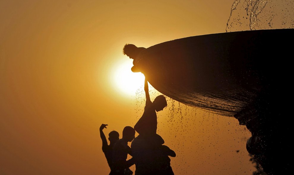 Unos niños cuelgan de una fuente en Nueva New Delhi, India. REUTERS/Anindito Mukherjee