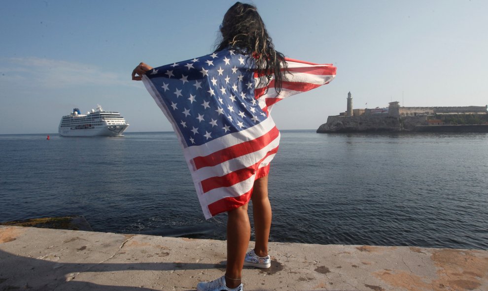 Una mujer con una bandera de Estados Unidos observa la llegada del primer crucero en navegar entre Estados Unidos y Cuba desde 1959. REUTERS