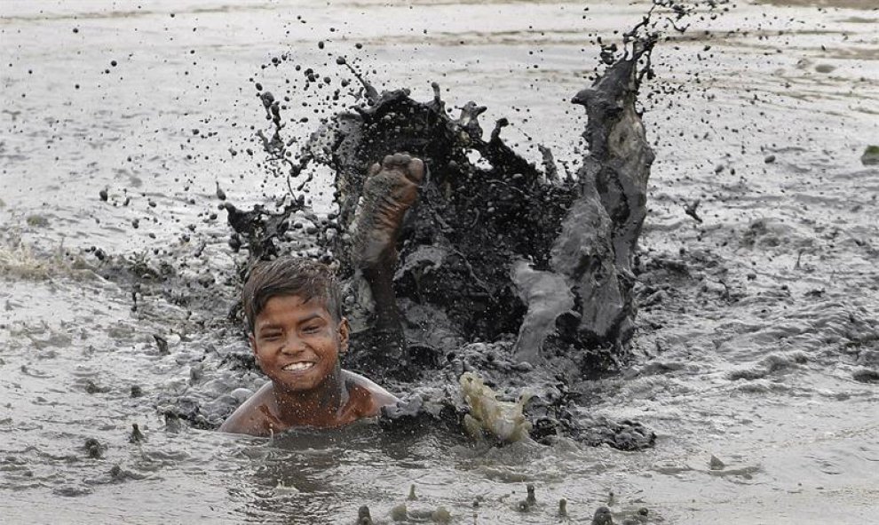 Un niño juega en una charca con agua contaminada durante un día caluroso en Nueva Delhi, India. EFE/Str