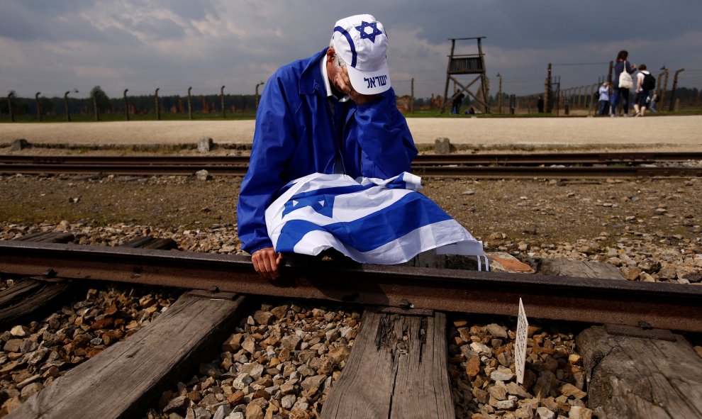 Un hombre sentado junto a las vías del tren del campo de concentración nazi de Auschwitz-Birkenau. REUTERS/Kacper Pempel