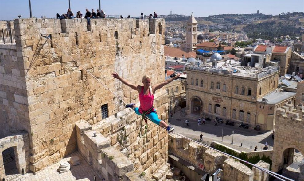 La estadounidense Heather Larsen mantiene el equilibrio sobre un cable atado entre dos torres en el complejo de la ciudadela de la Torre de David en el casco viejo de Jerusalén, Israel. EFE/Jim Hollander