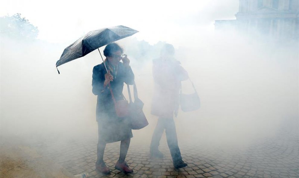 Dos mujeres intentan protegerse del humo provocado por los gases lacrimógenos lanzados durante un enfrentamiento entre agentes antidisturbios y manifestantes contra la reforma laboral en París, Francia EFE/Yoan Valat