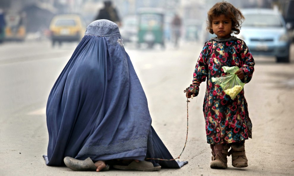 Una mujer ataviada con el burka y su hija piden lismona en una carretera de Peshawar, Pakistán. EFE/Arshad Arbab