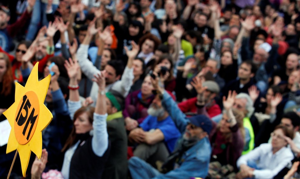 People raise their hands as they sit-in during a march to mark the 5th anniversary of the "indignados" movement in Madrid, Spain, May 15, 2016. REUTERS/Sergio Perez