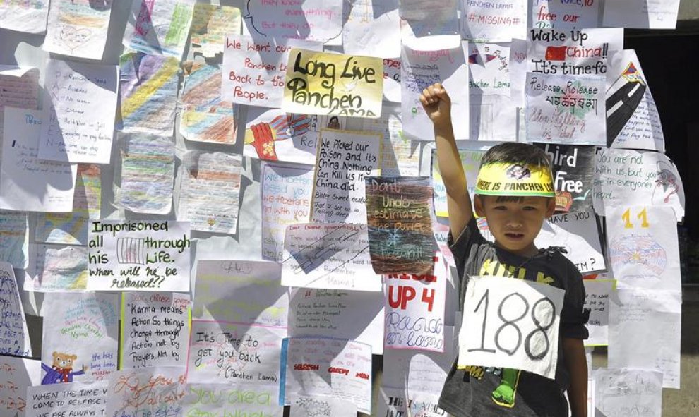 Un niño posa delante de una pared cubierta con mensajes de activistas tibetanos con motivo de la conmemoración del 21 aniversario del secuestro de un niño tibetano de siete años considerado como la reencarnación del Panchen Lama, en Dharamshala, India. EF