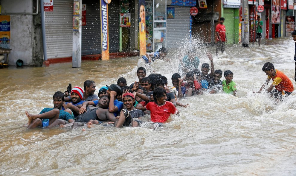 Unos jóvenes juegan por las calles inundadas antes de ser desaojados de sus casas en Biyagama, Sri Lanka. REUTERS/Dinuka Liyanawatte