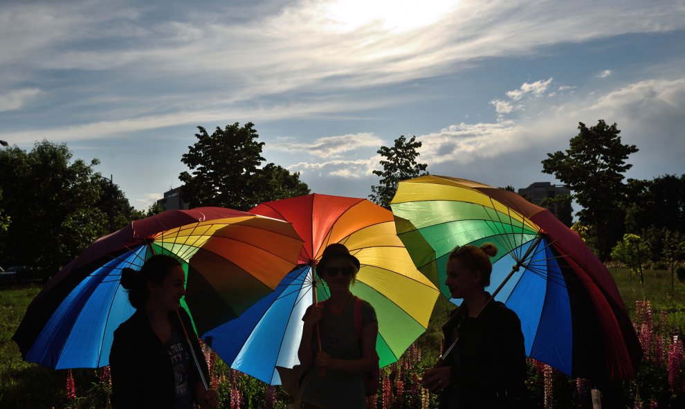 Personas sostienen paraguas arco iris para celebrar el Día Internacional contra la Homofobia frente al edificio del Parlamento rumano en Bucarest. DANIEL MIHAILESCU / AFP