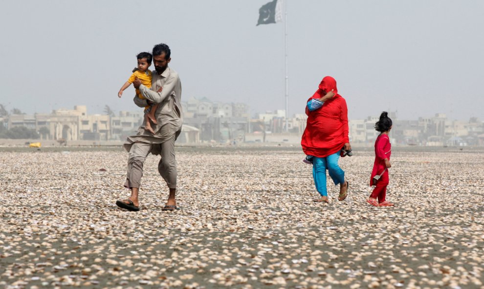 Una mujer se cubre el rostro con la bufanda para evitar el calor mientras camina con su familia por la playa en un día caluroso de verano en Karachi, Pakistán. REUTERS/Akhtar Soomro