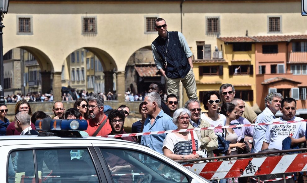 Varios curiosos congregados para ver las labores de rescate de los vehículos engullidos por un socavón cerca del famoso Puente Viejo a orillas del río Arno, en el centro de la ciudad italiana de Florencia (Italia). EFE/Maurizio Degl' Innocenti