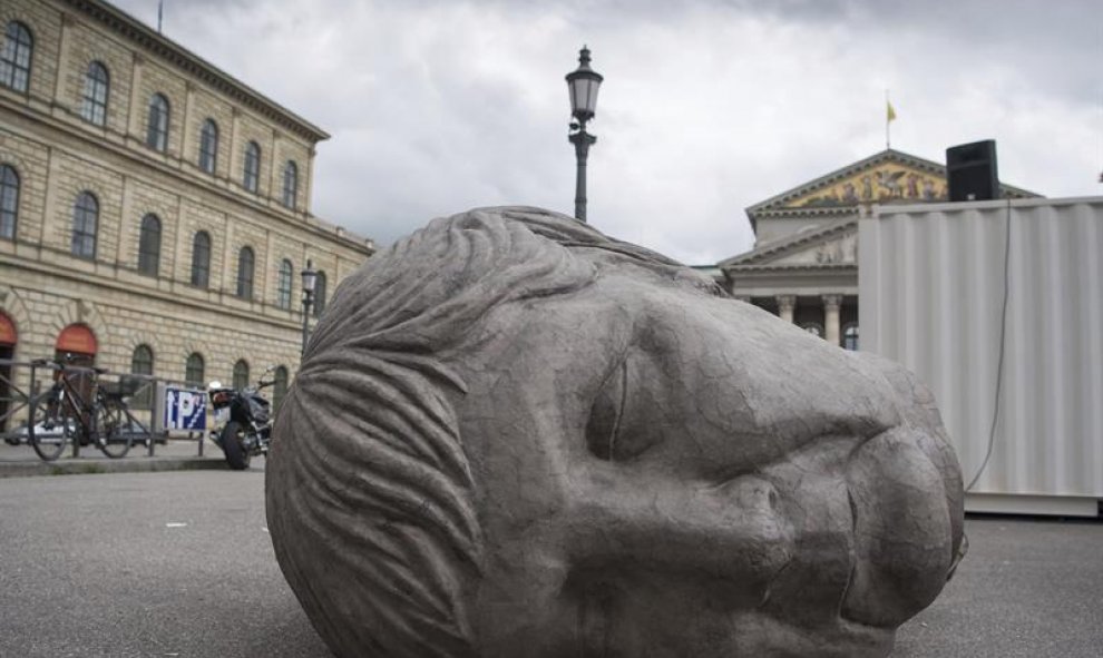 Una escultura gigante que representa la cabeza de la canciller alemana, Angela Merkel, yace en la plaza Max-Joseph-Platz delante de la Ópera en Múnich, Alemania. EFE/Peter Kneffel