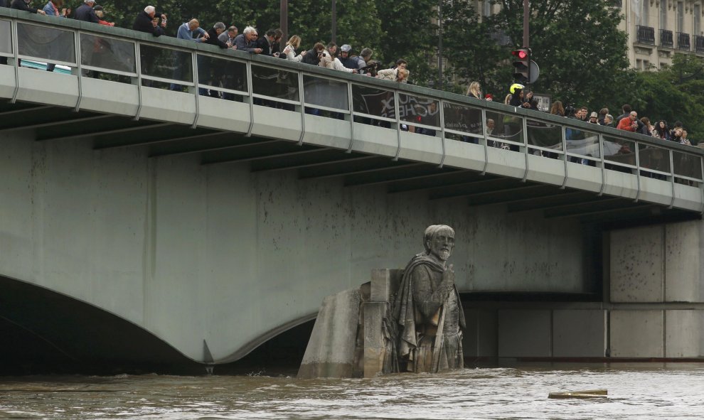 Algunas persoas observan cómo la crecida del Sena cubre la estatua de Zouave en el Puente del Alma, en París. REUTERS/Pascal Rossignol