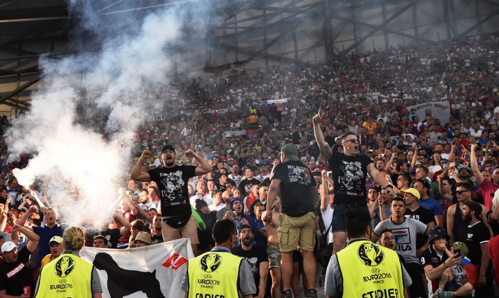 Radicales cantan y encienden una bengala en las gradas del estadio Vélodrome ante agentes de seguridad. /AFP