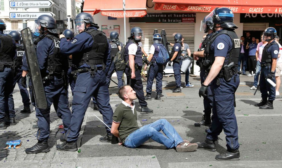 Un hincha esposado y sentado ante decenas de policías antidisturbios en Marsella. /REUTERS