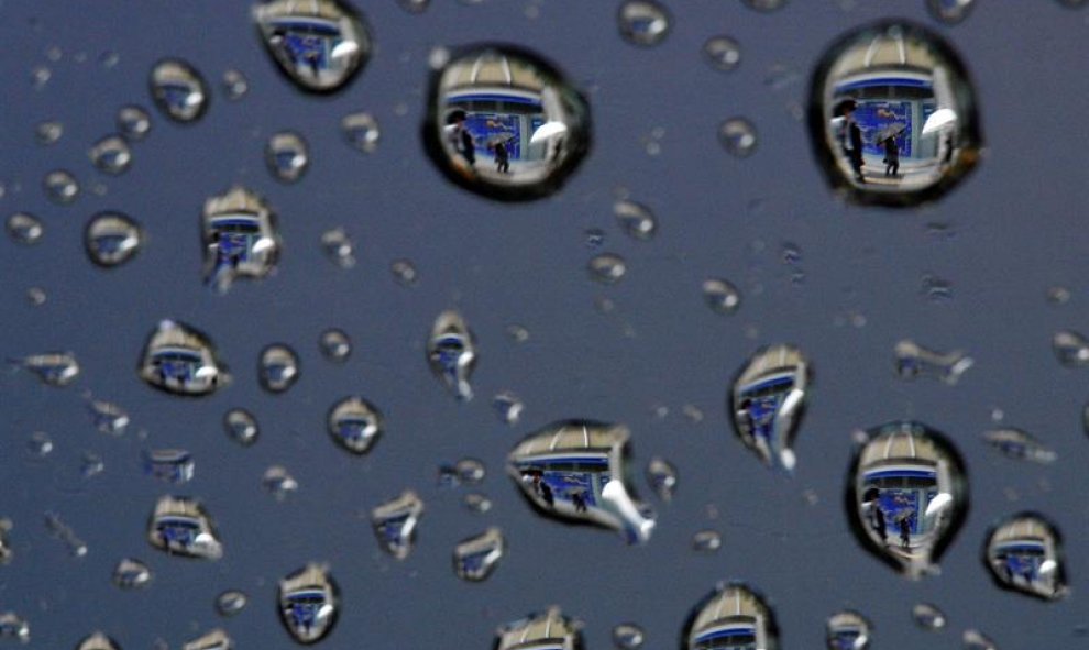 Una imagen rotada 180 grados, muestra gotas de lluvia que reflejan una pantalla que muestra información bursátil en Tokio, Japón. EFE/Franck Robichon