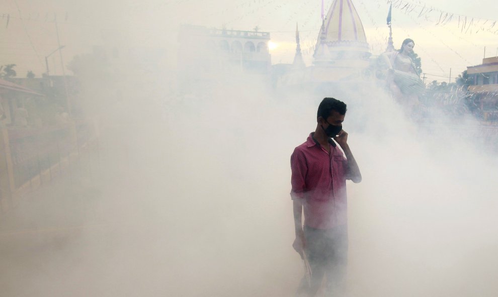 Un hombre cubre su cara mientras los trabajadores municipales fumigan el interior de un templo en Agartala, India. REUTERS/Jayanta Dey