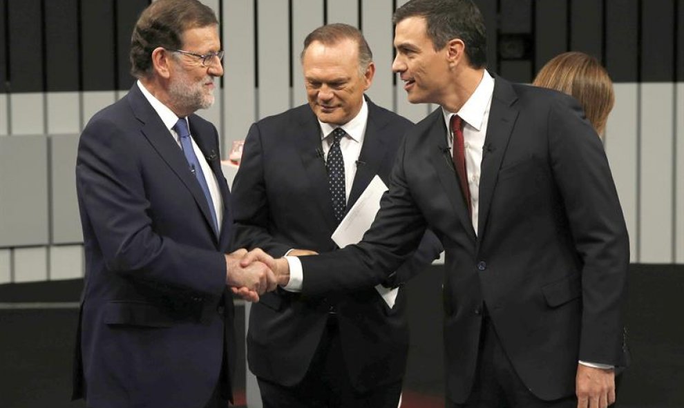 El presidente del Gobierno en funciones y del PP, Mariano Rajoy (i) saluda al líder del PSOE, Pedro Sánchez (d), ante uno de los moderadores del programa, Pedro Piqueras (c), en el plató momentos antes de iniciar el único debate a cuatro de la campaña ele