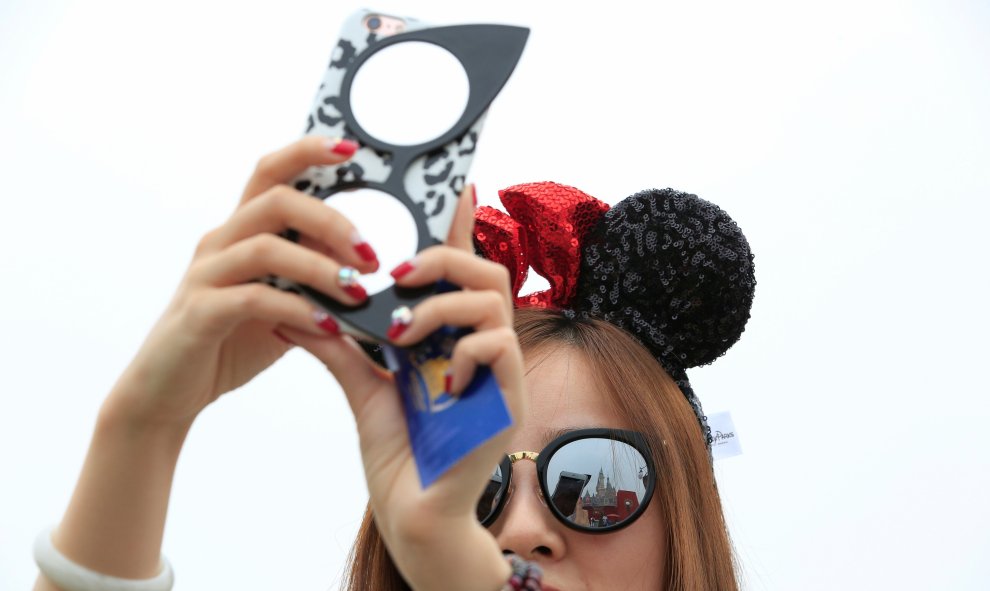Una chica saca fotos durante la ceremonia de inauguración con unas orejas de Mickey, el producto más deseado