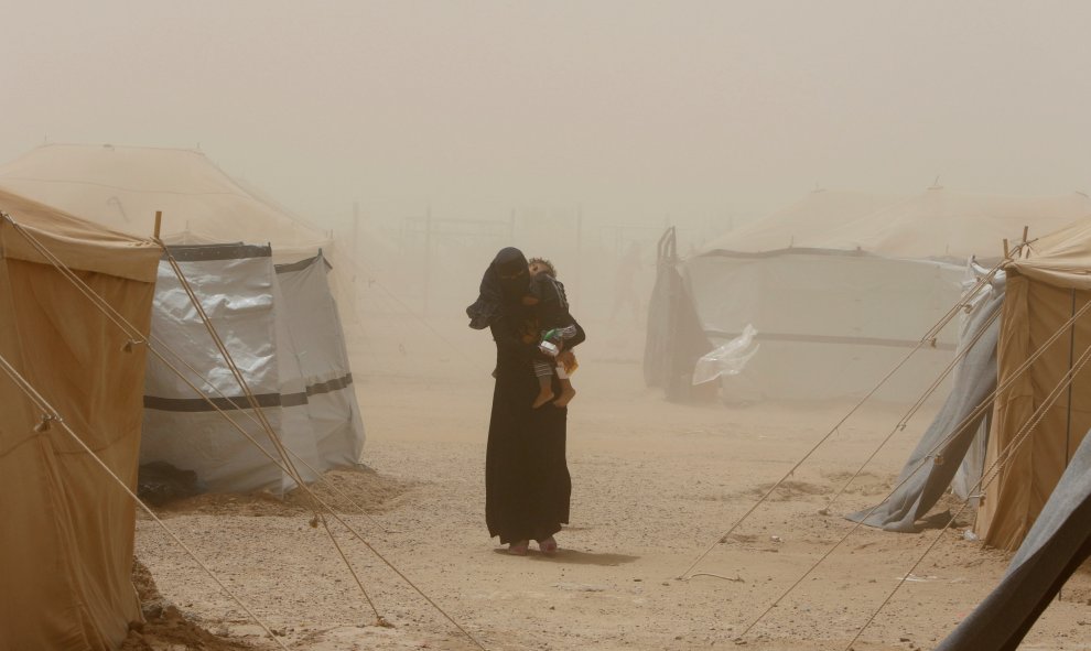 Una mujer que escapa de Faluya por el Estado Islámico cargando con su hijo durante una tormenta de arena al sur de Faluya, Iraq. REUTERS/Ahmed Saad