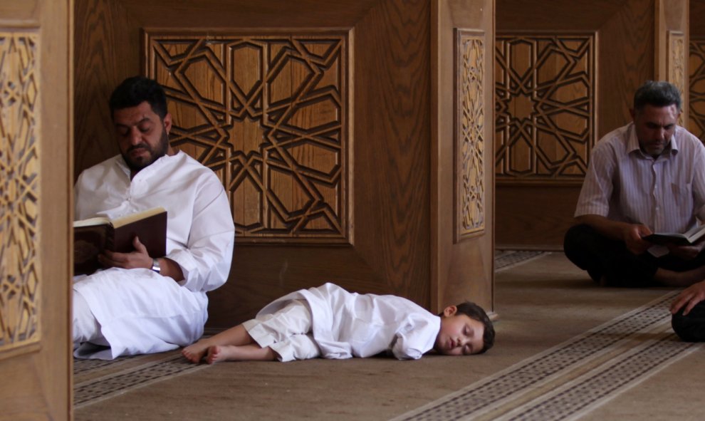 Un hombre lee el Corán mientras un niño se duerme en una mezquita en Siria. REUTERS/Khalil Ashawi