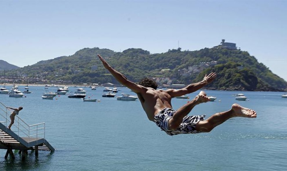 Un joven salta en el Real Club Náutico de San Sebastián, donde se ha podido disfrutar de una jornada playera en el último día de la primavera. EFE/Javier Etxezarreta