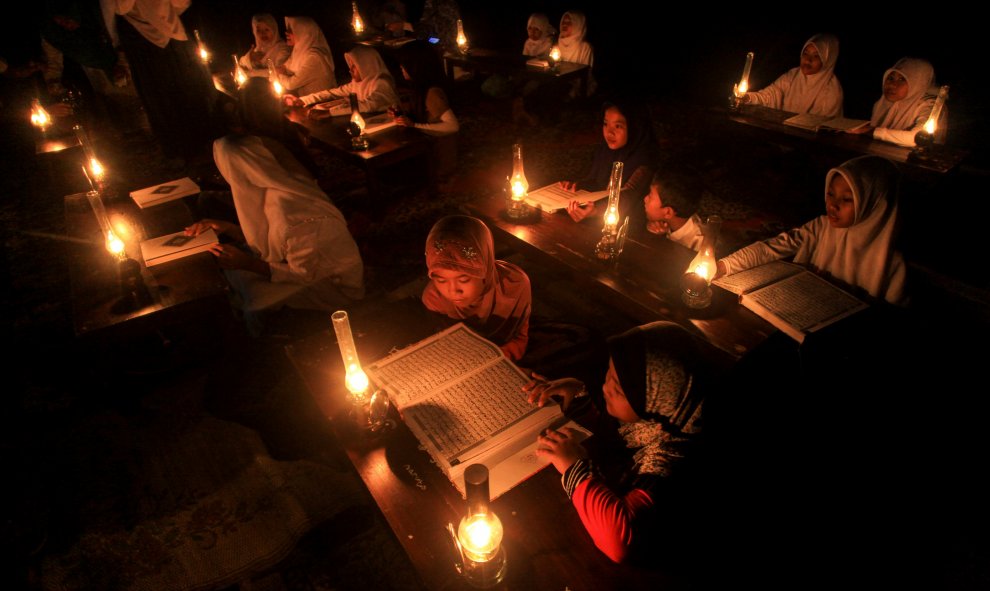 Estudiantes leen el Corán al aire libre iluminados por lámparas de aceite para celebrar el " Nuzul al- Corán " en Solo , Java Central, Indonesia.- REUTERS