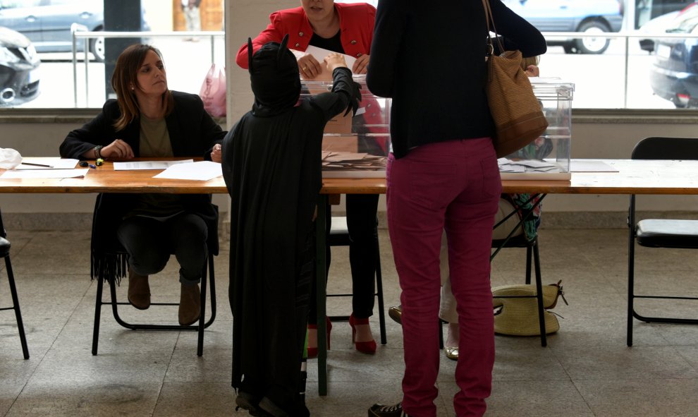 Un niño vestido de Batman deposita el voto de su madre en Pola de Siero. REUTERS/Eloy Alonso