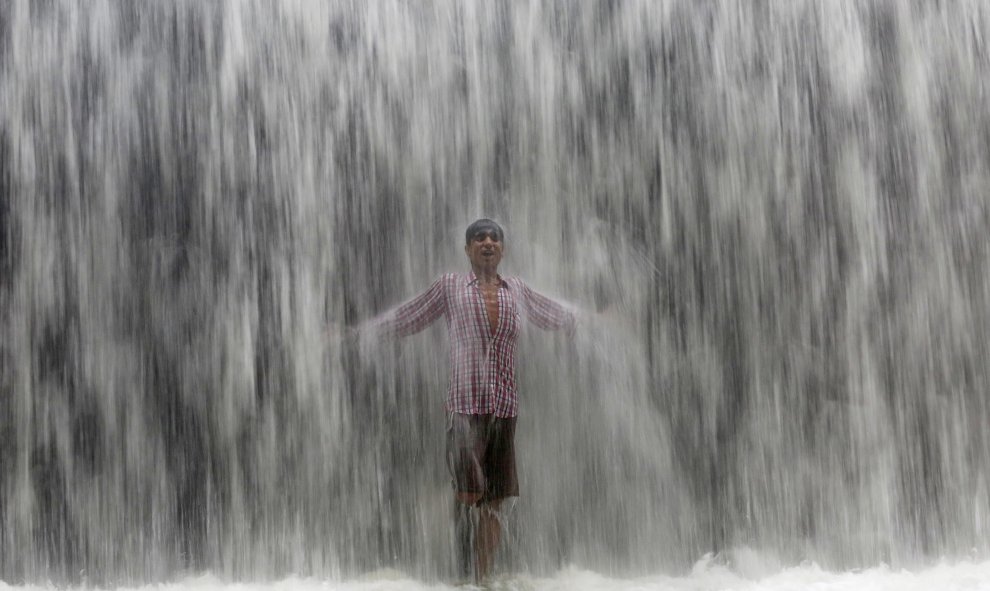 Un niño bajo el agua emanada de una presa  a lo largo del lago Powai tras fuertes lluvias en Mumbai , India.- REUTERS / Shailesh Andrad
