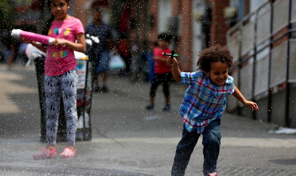 Un niño corre a través del agua que emana una boca de incendio en el barrio neoyorquino de Queens.  REUTERS/Shannon Stapleton.