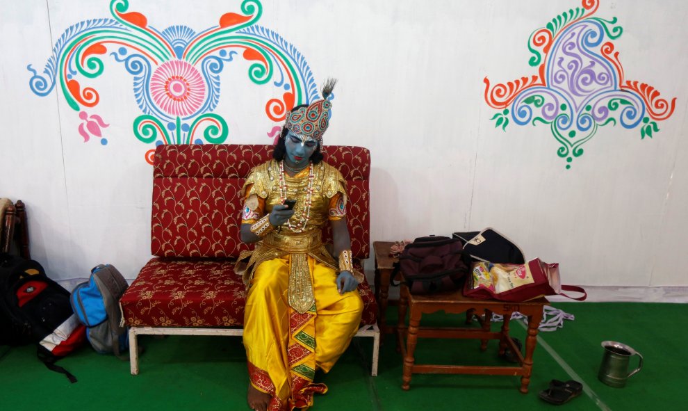 Artista caracterizado como Krishna usa su teléfono móvil mientras espera para llevar a cabo el último día de la semana de celebración del Señor Jagannath " Rath Yatra " , o la procesión del carro, en Calcuta , India.- REUTERS