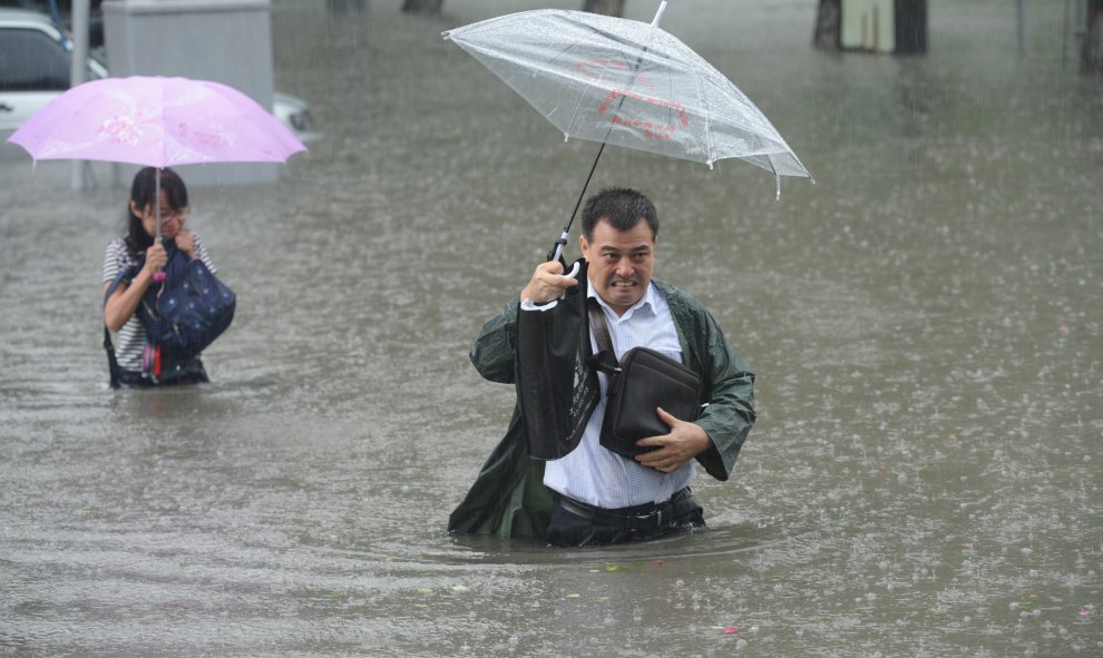 Un hombre lleva su paragüas mientras atravisa la calle entre las aguas a causa de las inundaciones en Taiyuan, en la provincia de Shanxi Province, China. China Daily/REUTERS