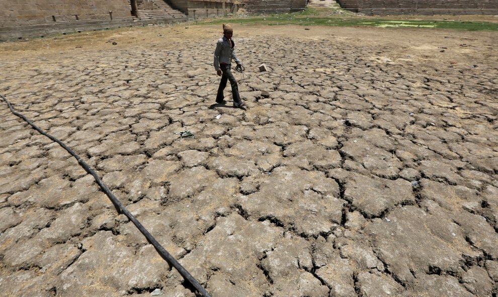 Un hombre atraviesa el lago Sarkhej en la India, que se ha secado a causa del intenso calor que vive el país/REUTERS