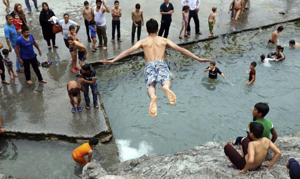 Un niño salta a la piscina de Cheshme-Ali en la antigua ciudad iraní de Ray, en la provincia de Teherán. Irán sufre una ola de calor con temperaturas que rondan los 40 grados. EFE/Abedin Taherkenareh