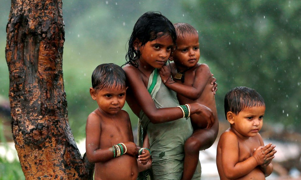 Unos niños se refugian de la lluvia bajo un árbol en Nueva Delhi, India. REUTERS/Adnan Abidi