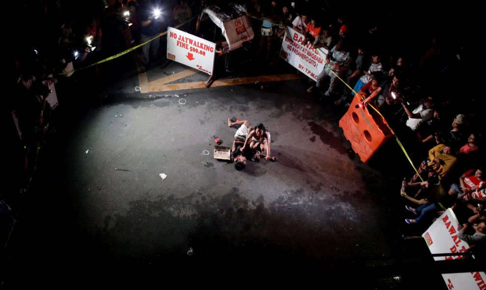 Jennelyn Olaires, de 26 años, llora sobre el cuerpo de su pareja, que fue asesinado en una calle por un grupo de vigilancia, según la policía, en una serie de asesinatos relacionados con las drogas en la ciudad de Pasay, Metro Manila, Filipinas. Un signo