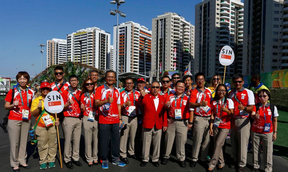 El equipo de Singapur, con carteles de su país, posan en su bienvenida a la Villa. /REUTERS