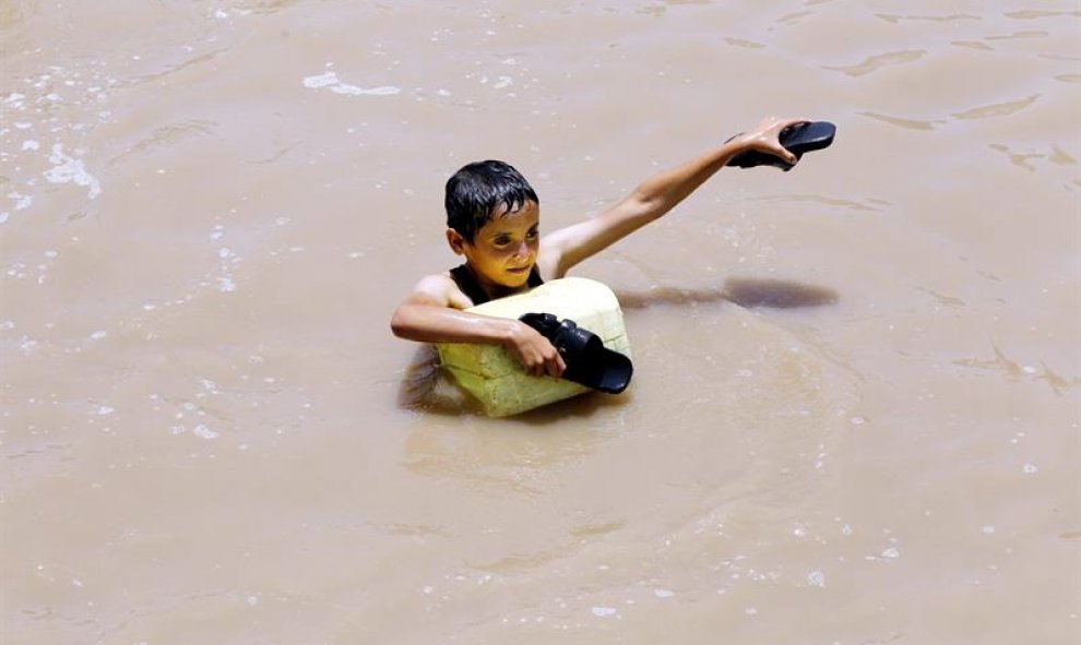 Un niño camina con el agua hasta los hombros por una calle inundada en Saná (Yemen). Al menos cinco personas han muerto a causas de las lluvias torrenciales que han sufrido varias regiones del país. EFE/Yahya Arhab
