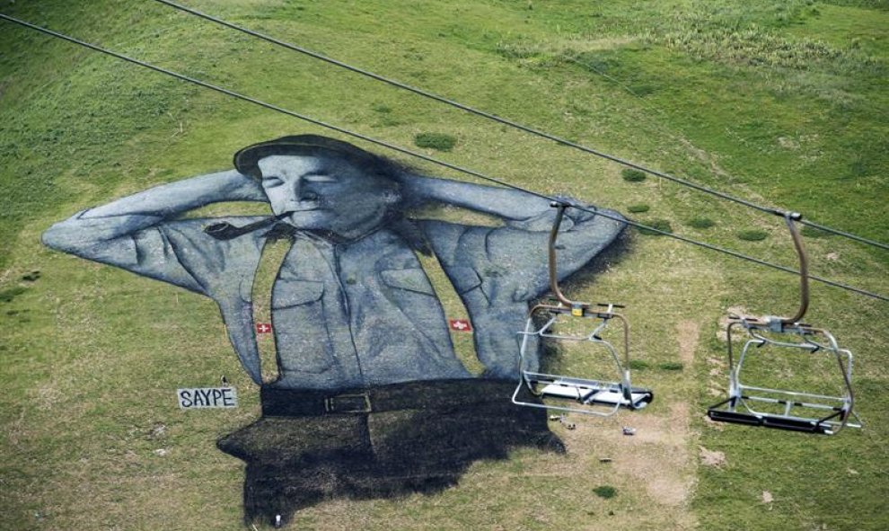Vista de una imagen que representa a un pastor suizo, hecha con pintura biodegradable, obra del artista francés Saype en 10,000 metros cuadrados de césped en Leysin, Suiza. EFE/Jean-Christophe Bott